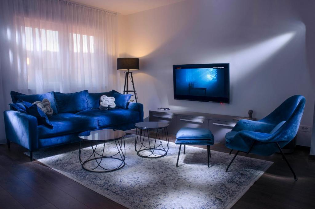 a living room with a blue couch and chairs and a tv at Villa Kap in Zagreb