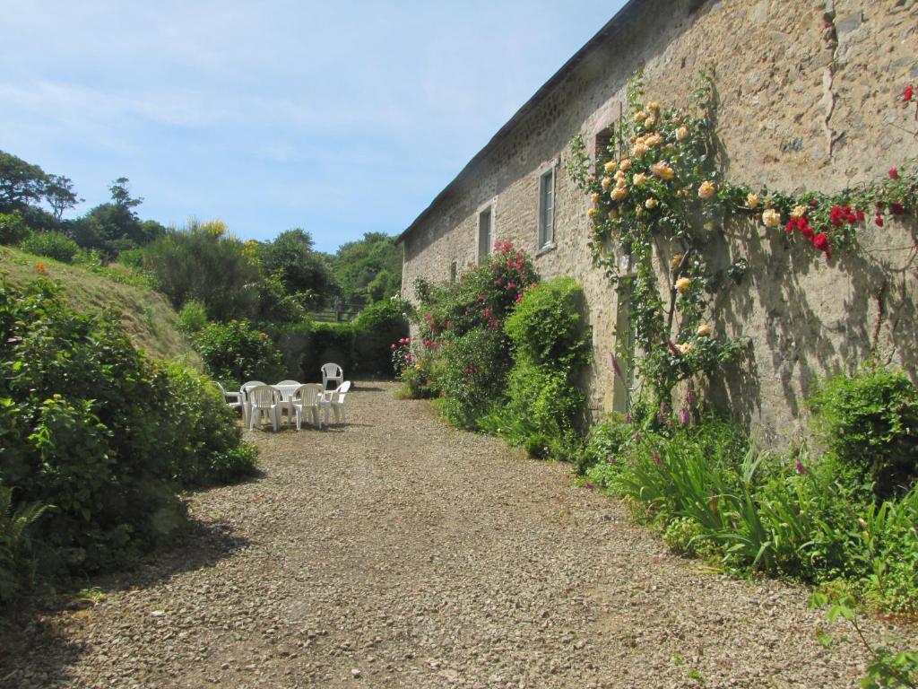 ein Steingebäude mit Blumen auf der Seite in der Unterkunft Gîte de La Ferme de La Cour in Crasville