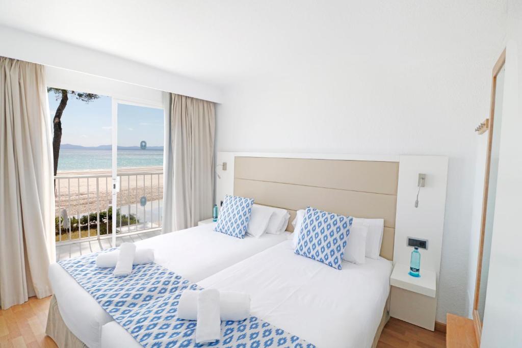 two beds in a bedroom with a view of the ocean at Bonavida Apartments in Port d'Alcudia