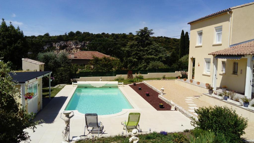 una piscina con 2 sillas y una casa en l'oustau bonur, en Bourg-Saint-Andéol