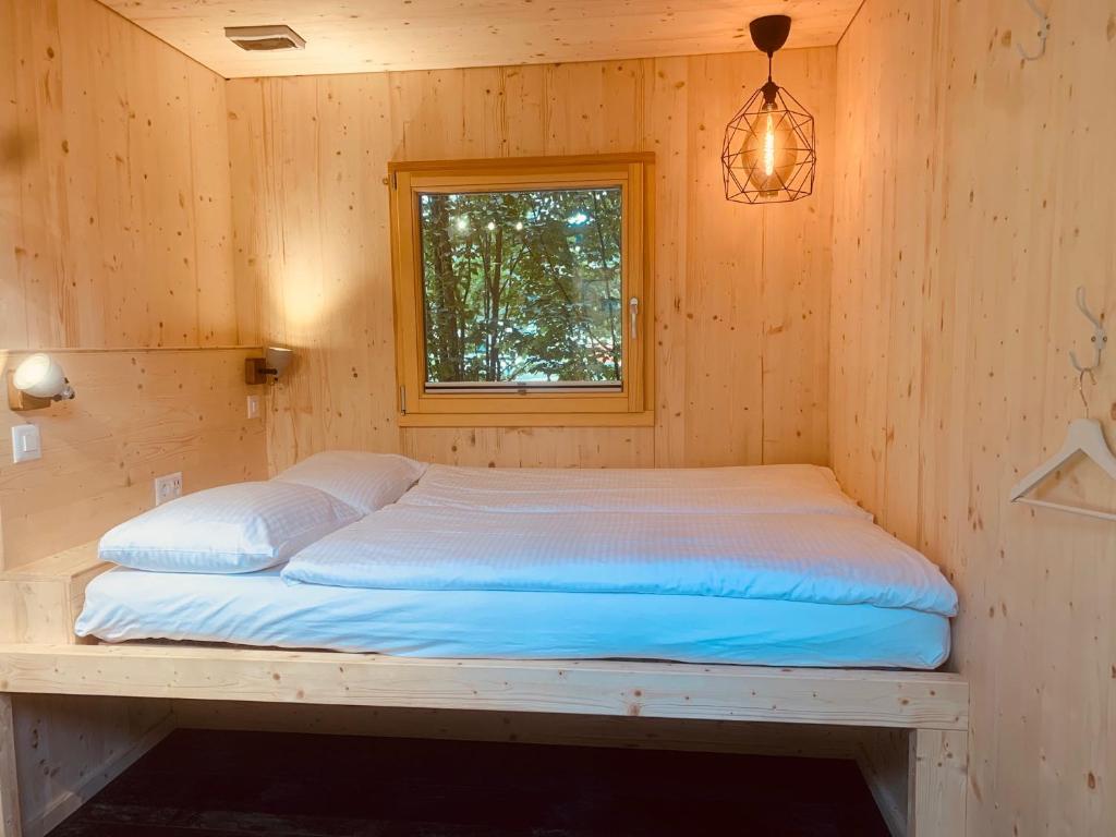 a bed in a wooden room with a window at RiverLodge TCS Training & Freizeit AG in Interlaken