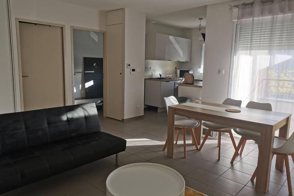 uma sala de estar com um sofá, uma mesa e cadeiras em Appartement T2 accessible PMR avec terrasse et garage em Onet le Château