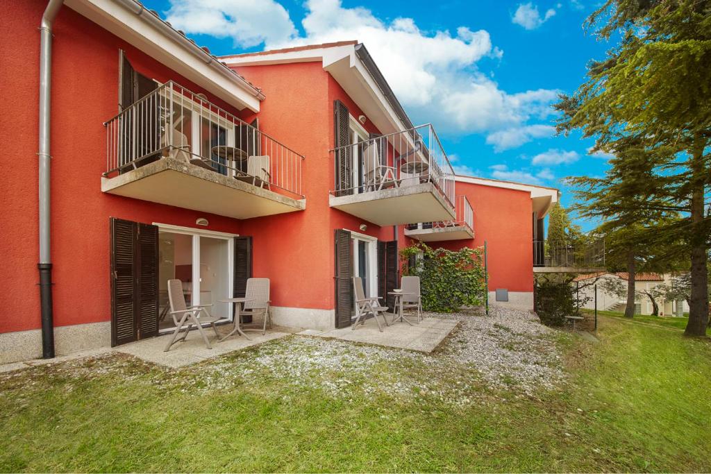 a red building with chairs and tables in a yard at Villa Adriatic - Hotel & Resort Adria Ankaran in Ankaran