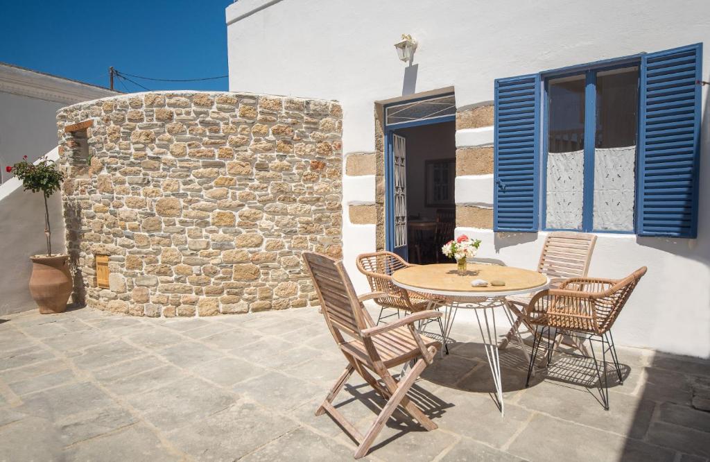 un patio con mesa, sillas y pared de piedra. en Anastasia Traditional House en Lardos
