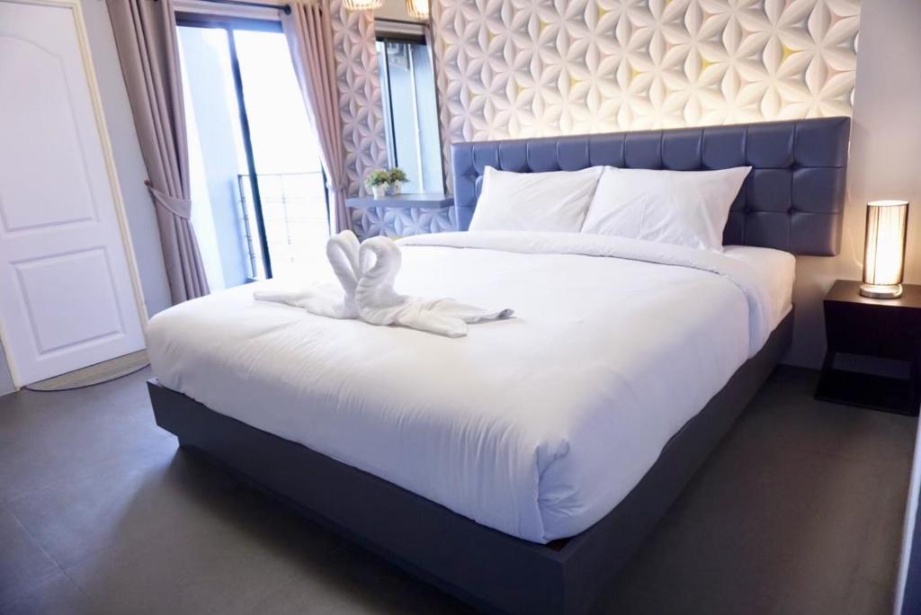 um quarto com uma grande cama branca e uma grande cabeceira de cama. em บันดารี่ ริชชี่ (Bhundaree Richy) em Hat Yai