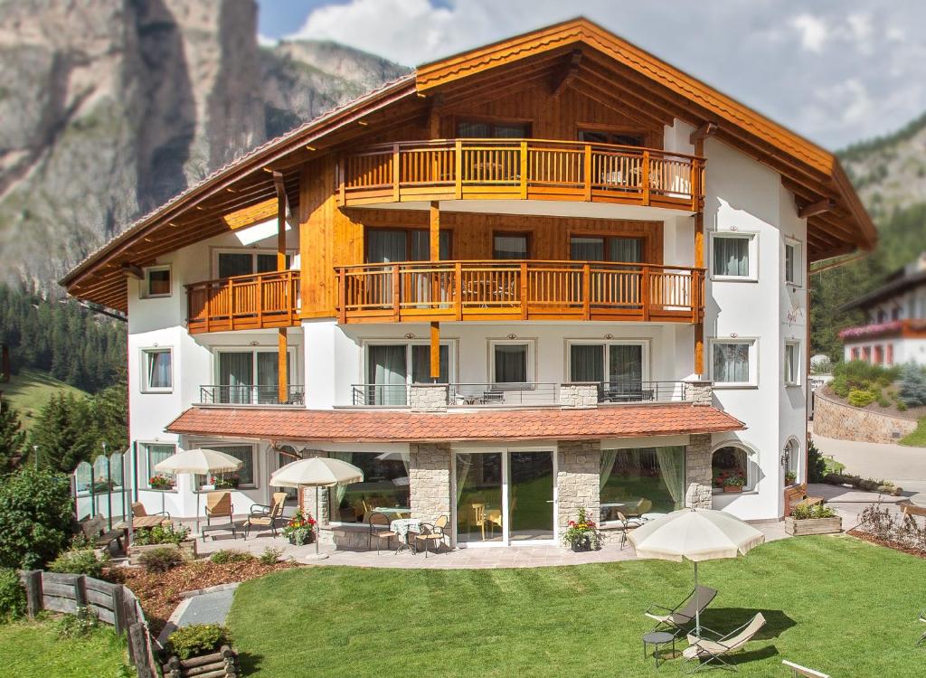 a large building with a balcony on top of a yard at Hotel Garni Aghel in Selva di Val Gardena