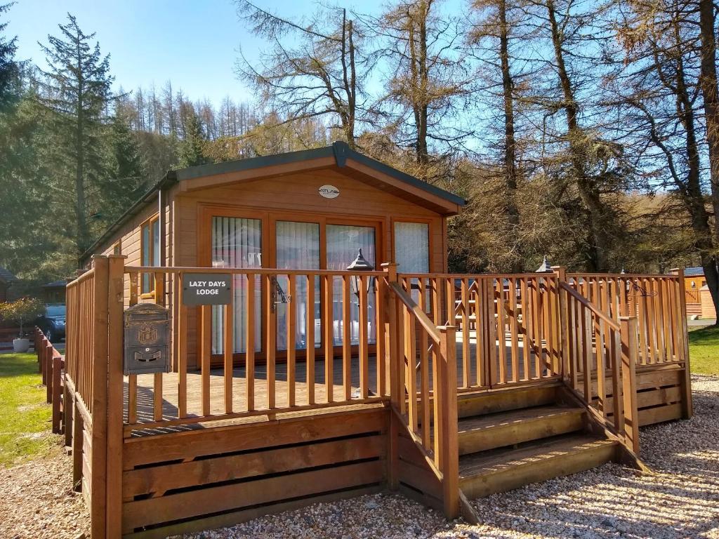 a small cabin with a staircase and a fence at Lazy Days Lodge in Glendevon