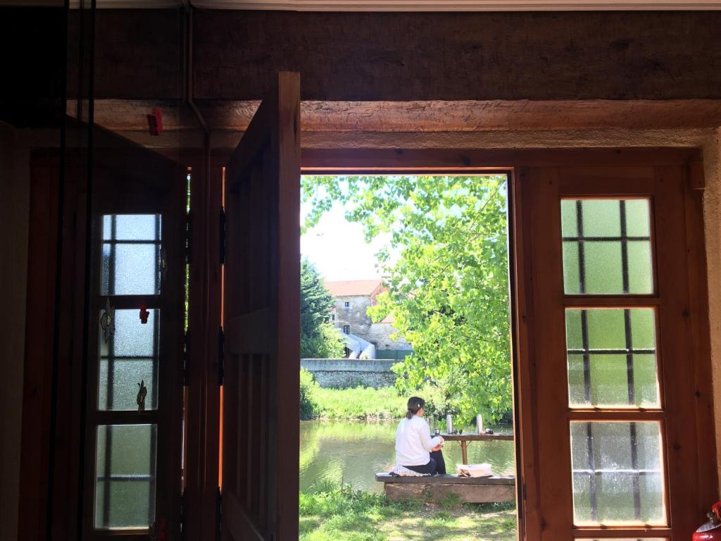 una persona sentada en un banco mirando por una ventana en Casa Rural La Casita del Río, en Villarcayo