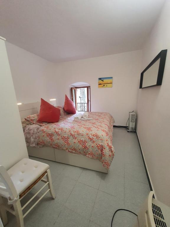 a bedroom with a bed with red pillows and a chair at Monolocale caterina in Corniglia