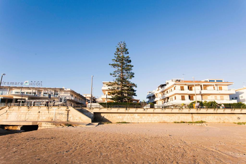 a bridge over a beach with buildings and a tree at Case Madira in Marina di Ragusa