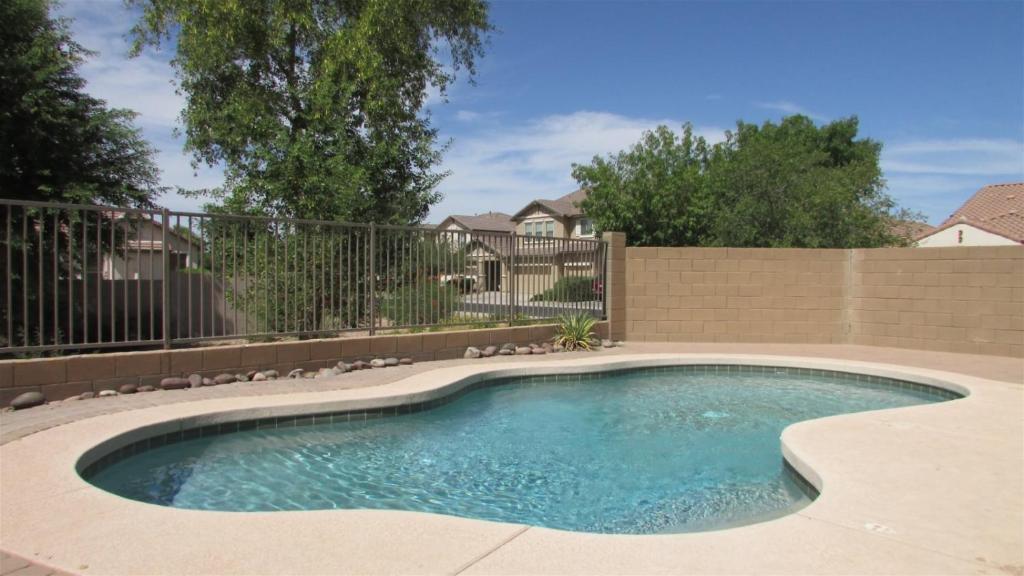 a swimming pool in a yard with a fence at Gated house near South Mountain with pool heater, BBQ in Phoenix