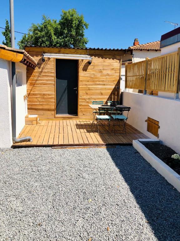 une terrasse en bois avec une table de pique-nique devant un bâtiment dans l'établissement charmant T1, au Grau-dʼAgde