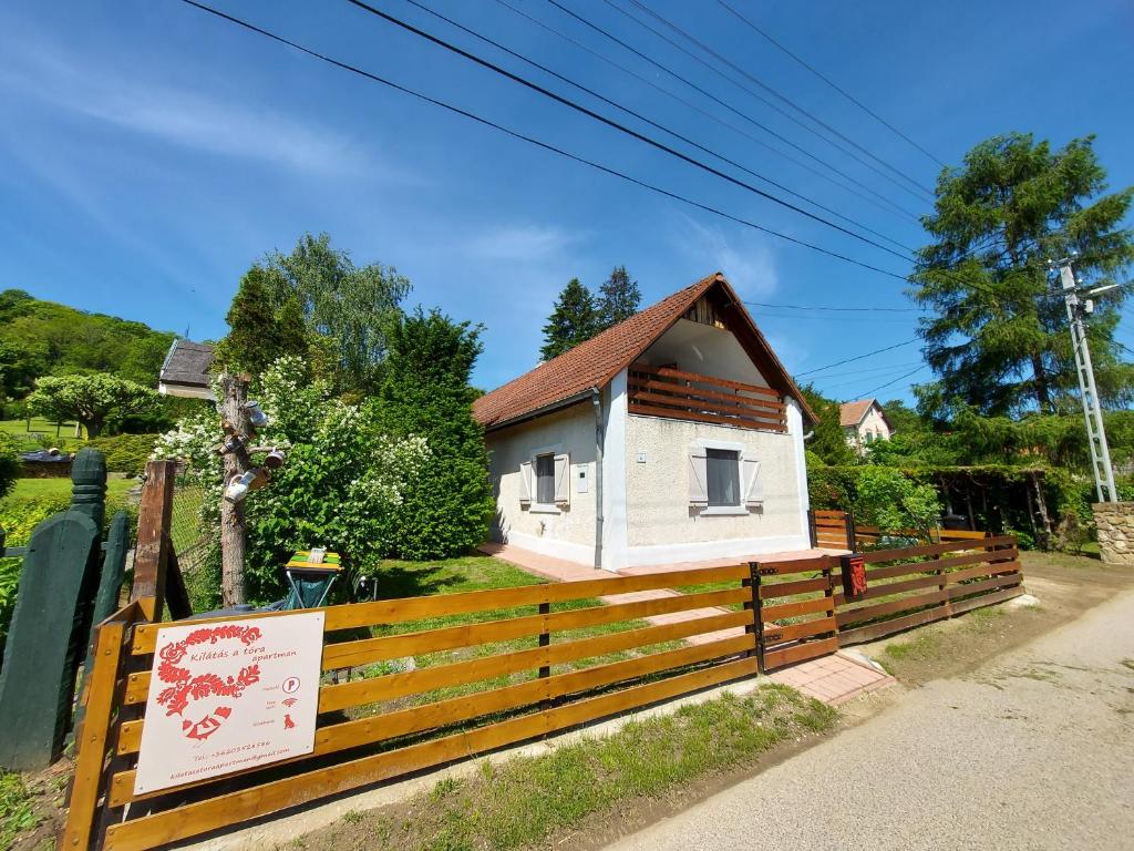 una pequeña casa blanca detrás de una valla de madera en Kilátás a tóra Apartman, en Szigliget