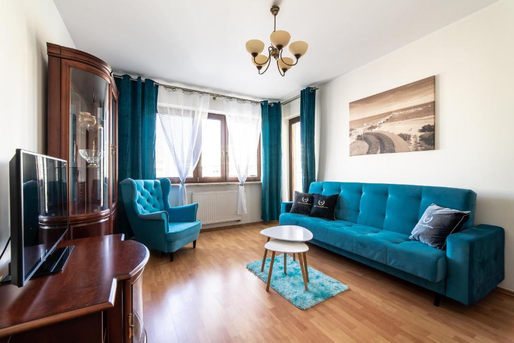- un salon avec un canapé bleu et une table dans l'établissement Apartamenty Gdańsk EU - Apartament Jelitkowski, à Gdańsk