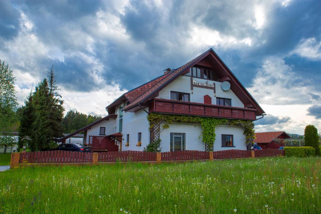 a white house with a red fence in a field at Bed and Breakfast Valjavec in Kranj