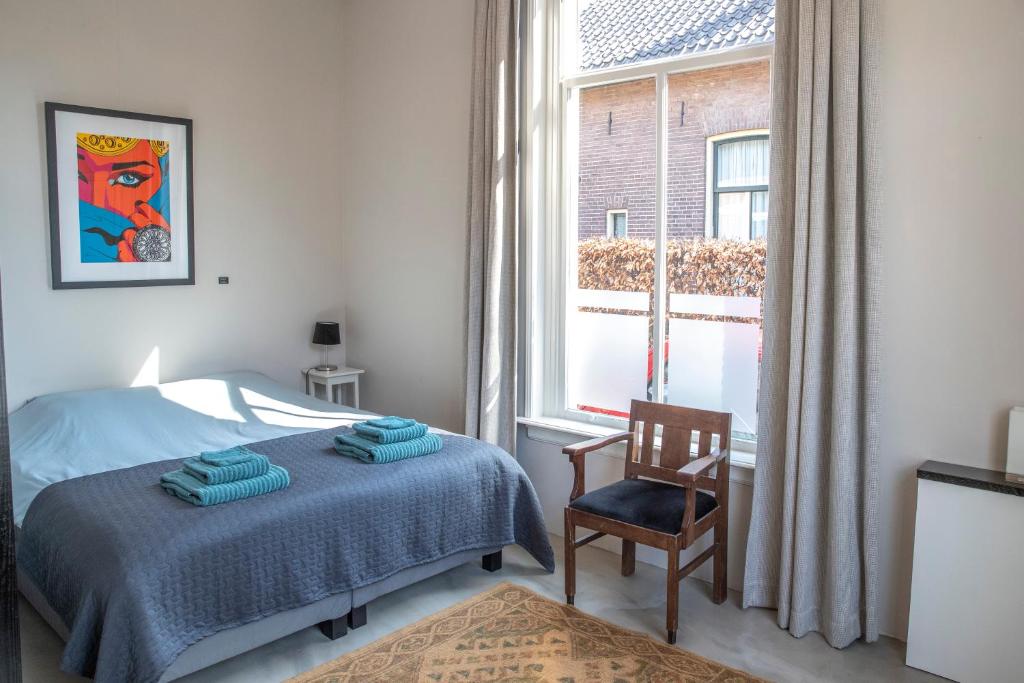 um quarto com uma cama, uma cadeira e uma janela em De Grift em Apeldoorn
