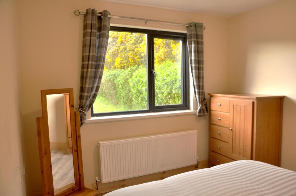 sypialnia z oknem, komodą i lustrem w obiekcie FOYLE VIEW CABIN w mieście Greencastle