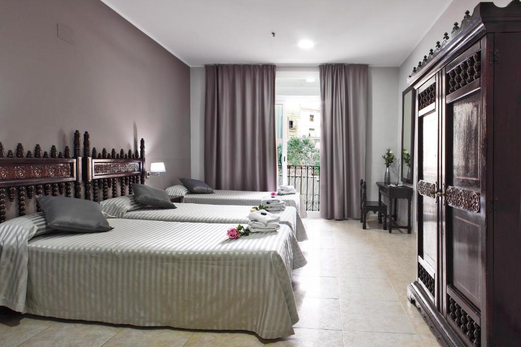 a bedroom with three beds and a balcony at Hotel Inglés in Barcelona