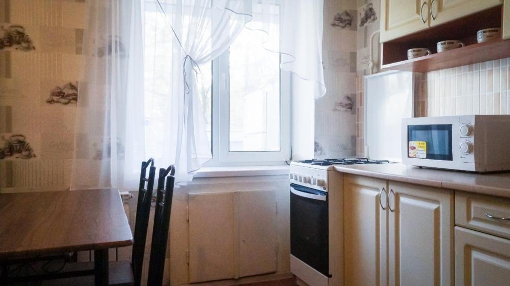 kuchnia z kuchenką mikrofalową, stołem i oknem w obiekcie Аккуратная , чистая квартира на Пр Гагарина 169 w mieście Dniepr