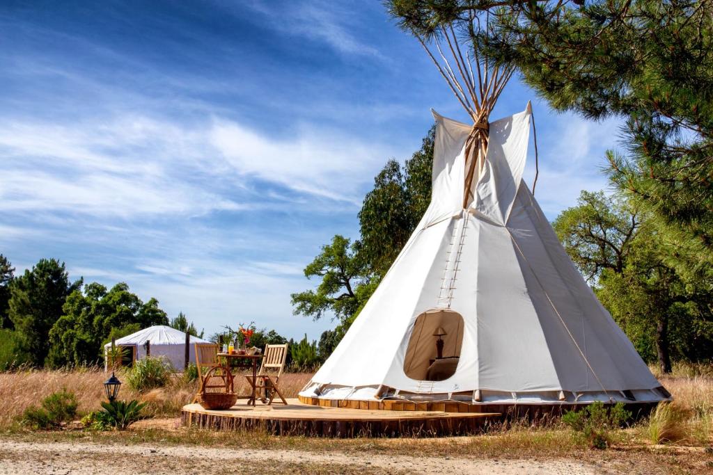 a teepee tent with a table and chairs in a field at Goodmuda Tipi's in Grândola
