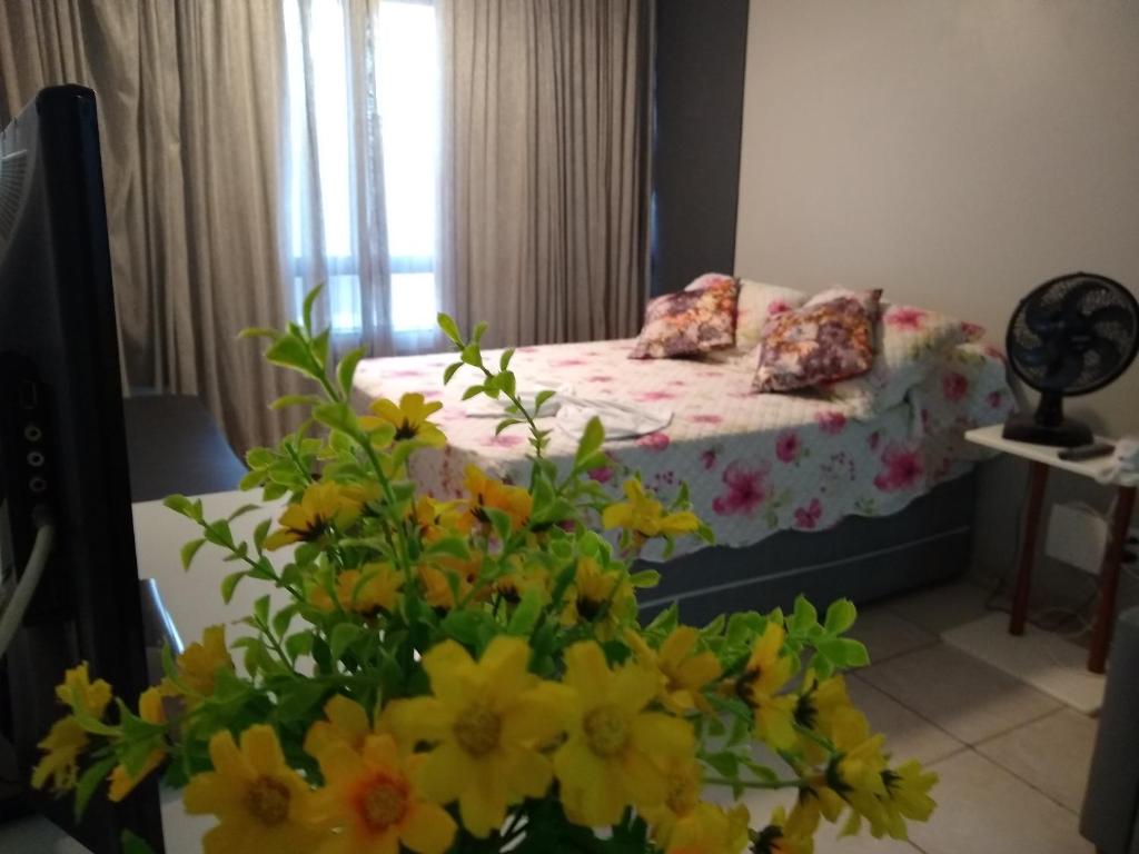 a bedroom with a bed with flowers in the foreground at Farol da Barra 209 in Salvador