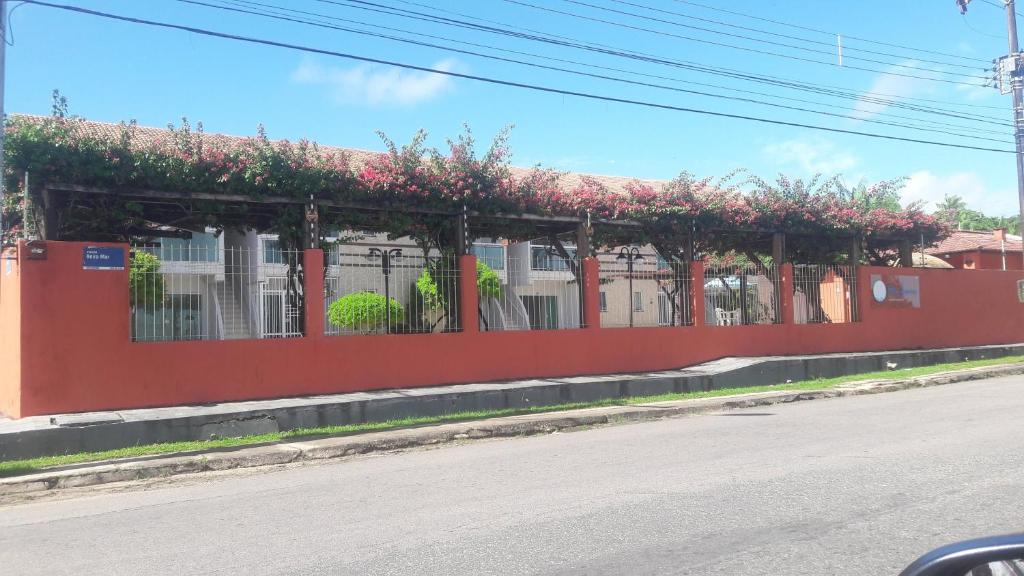 Una pared roja con flores rosas al lado de una calle en AP Comfort Feliz Aurora - Frente Praia do Ariramba, en Mosqueiro