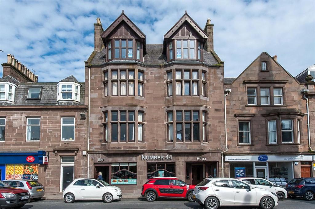 a large brick building with cars parked in front of it at Number 44 Hotel & Bar in Stonehaven