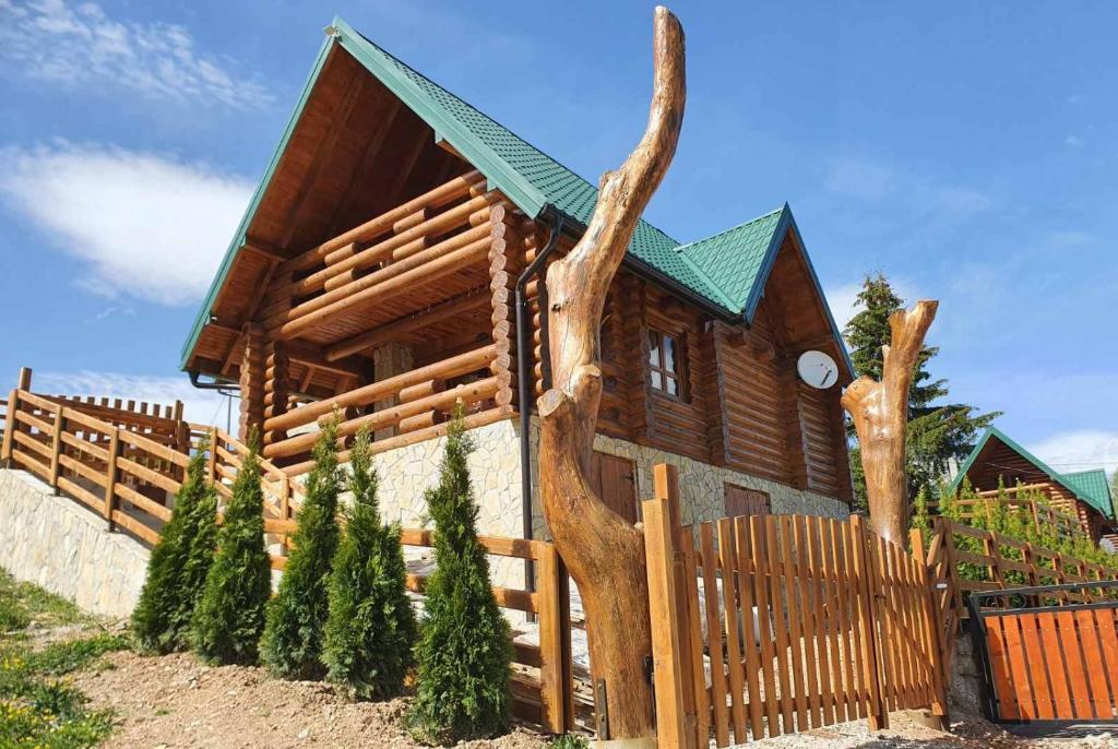 a log cabin with a fence and a tree trunk at Zlatar Luxury Chalet - TRACE OF NATURE 2214 in Nova Varoš