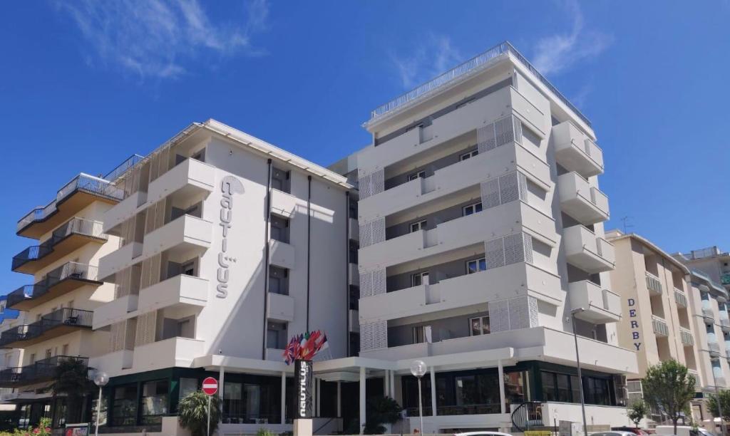 a white apartment building next to another building at Hotel Nautilus in Cattolica