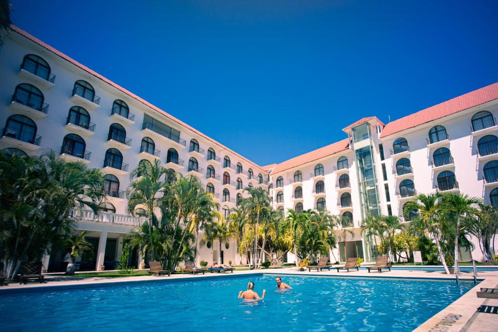 duas pessoas na piscina em frente a um hotel em Hotel Caracol Plaza em Puerto Escondido