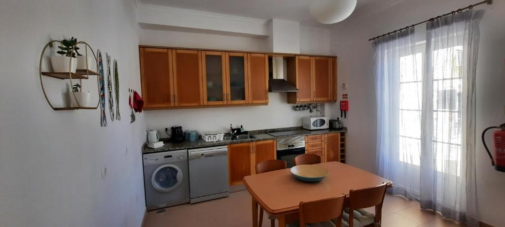 a kitchen with wooden cabinets and a table and a dining room at CasAzulApartments in Sintra