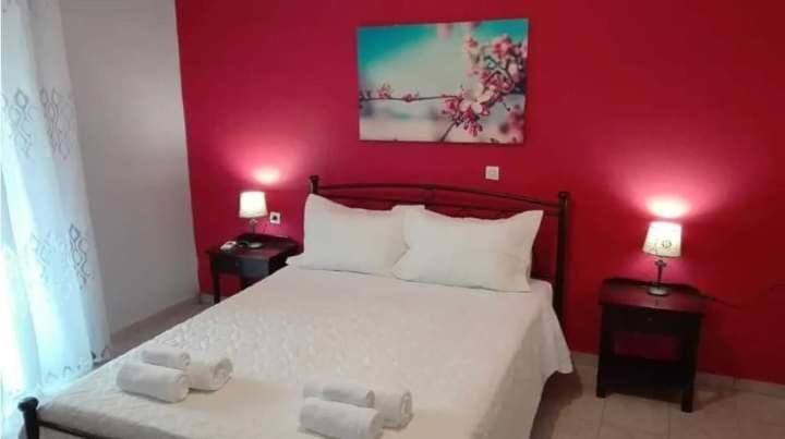 a bedroom with a white bed with a red wall at Katerina's home in Moraitika