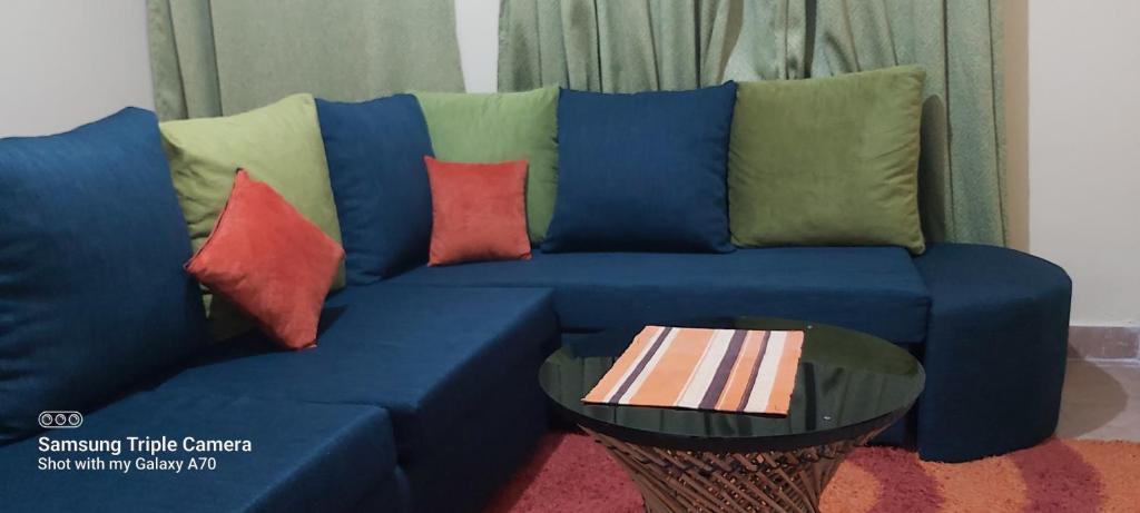 niebieska kanapa z kolorowymi poduszkami i stołem w obiekcie Annettes Place w mieście Naivasha
