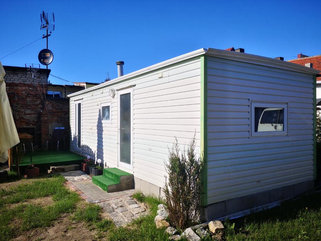 a small white trailer with a green door at Domek holenderski Lilla in Łeba