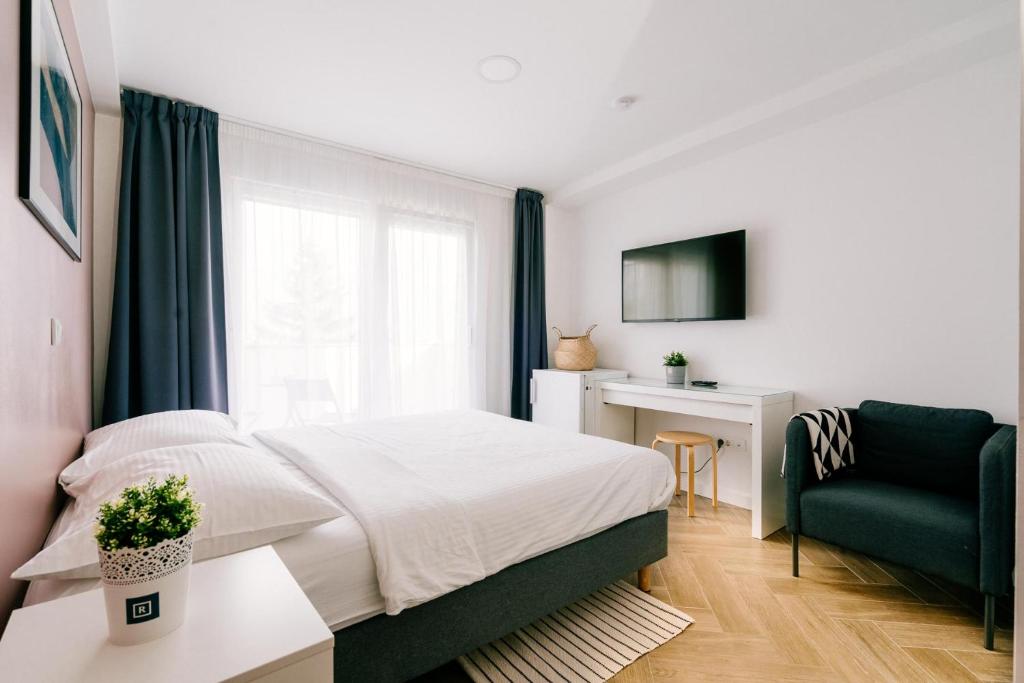 1 dormitorio con 1 cama y 1 silla en Rooms at Zajčeva 34, en Zagreb