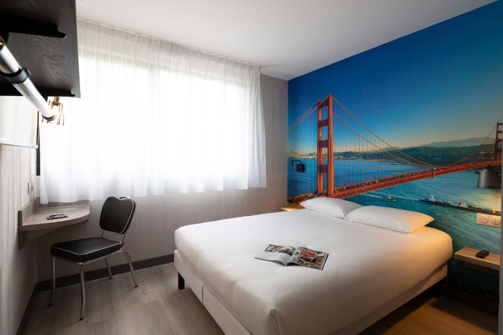 a bedroom with a bed with a painting of the golden gate bridge at Break Hôtel in Vierzon