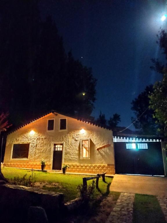 a stone house with a garage at night at Las Flores, casa del valle in Potrerillos