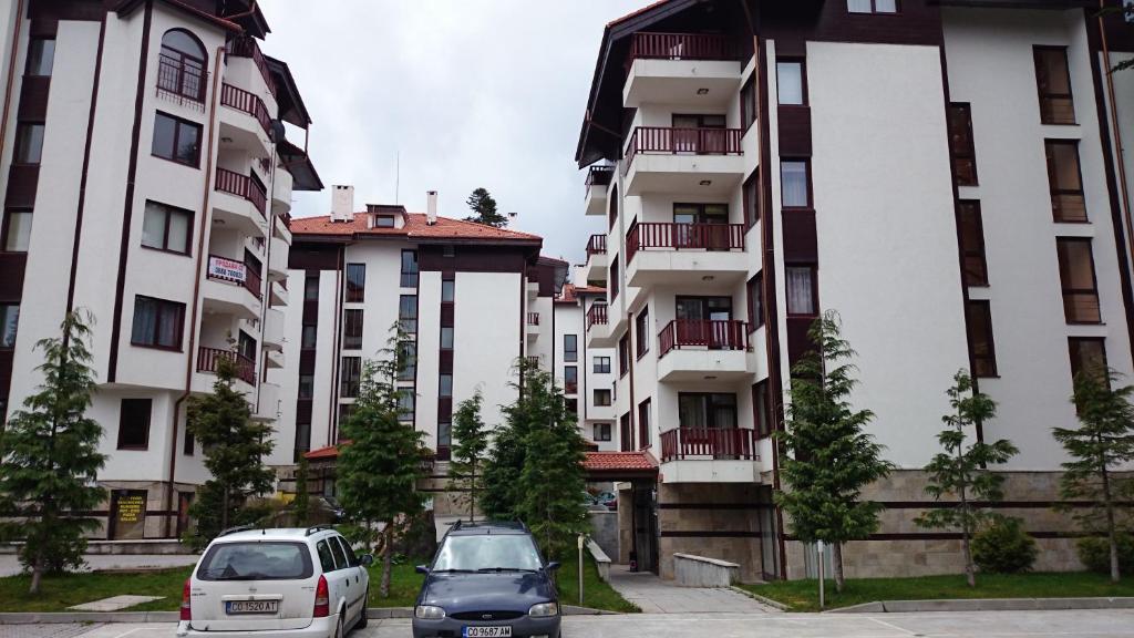 two cars parked in front of tall buildings at TES Flora Apartments in Borovets