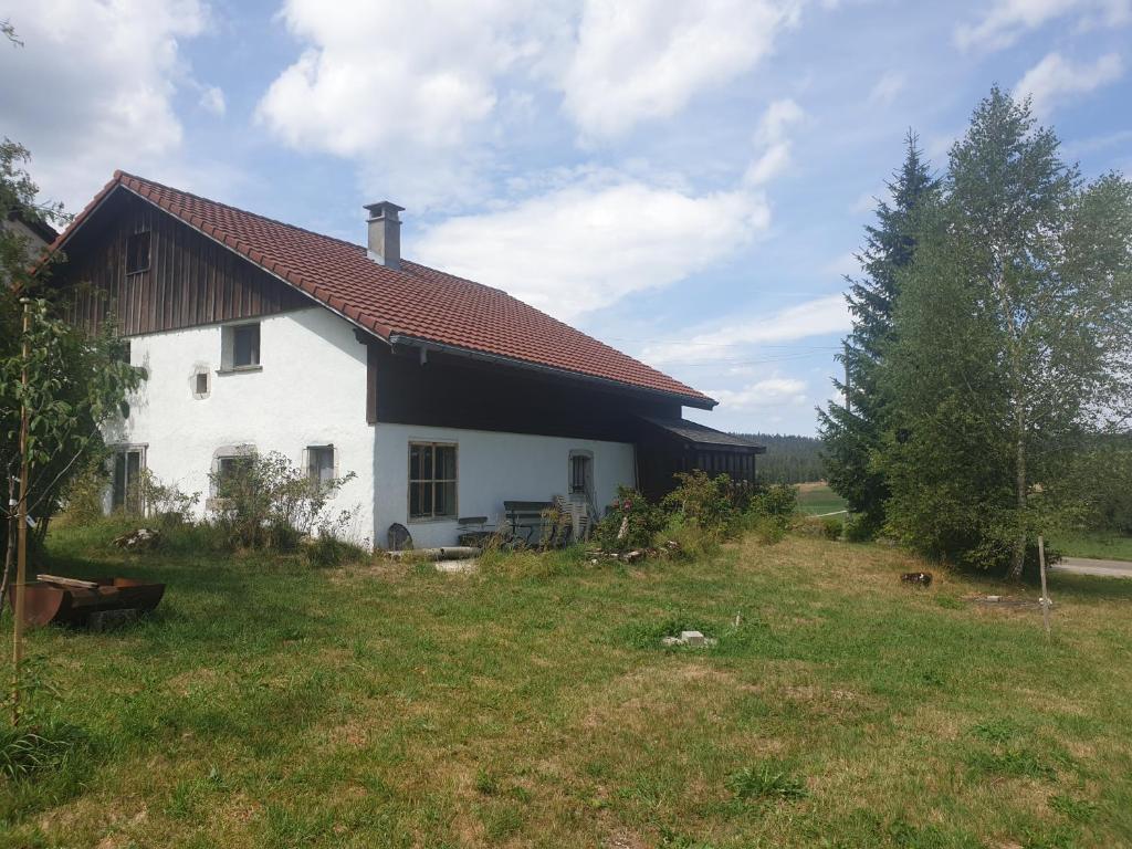 uma casa branca com um telhado castanho num campo em Le Petit Brouillet du bas em La Brévine