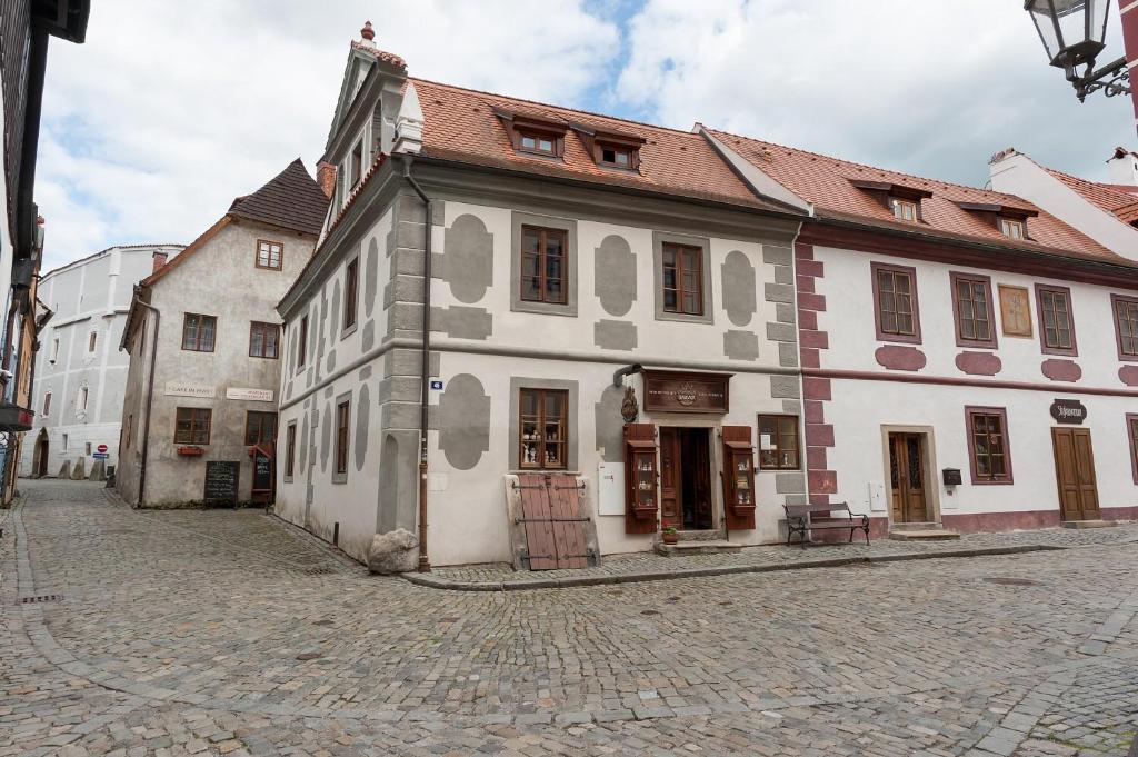 a white building with a brown roof on a street at Babyka Apartments in Český Krumlov