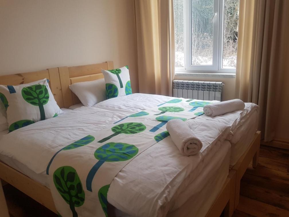 Cama con sábanas y almohadas verdes y blancas en Petit Dilijan, en Dilijan