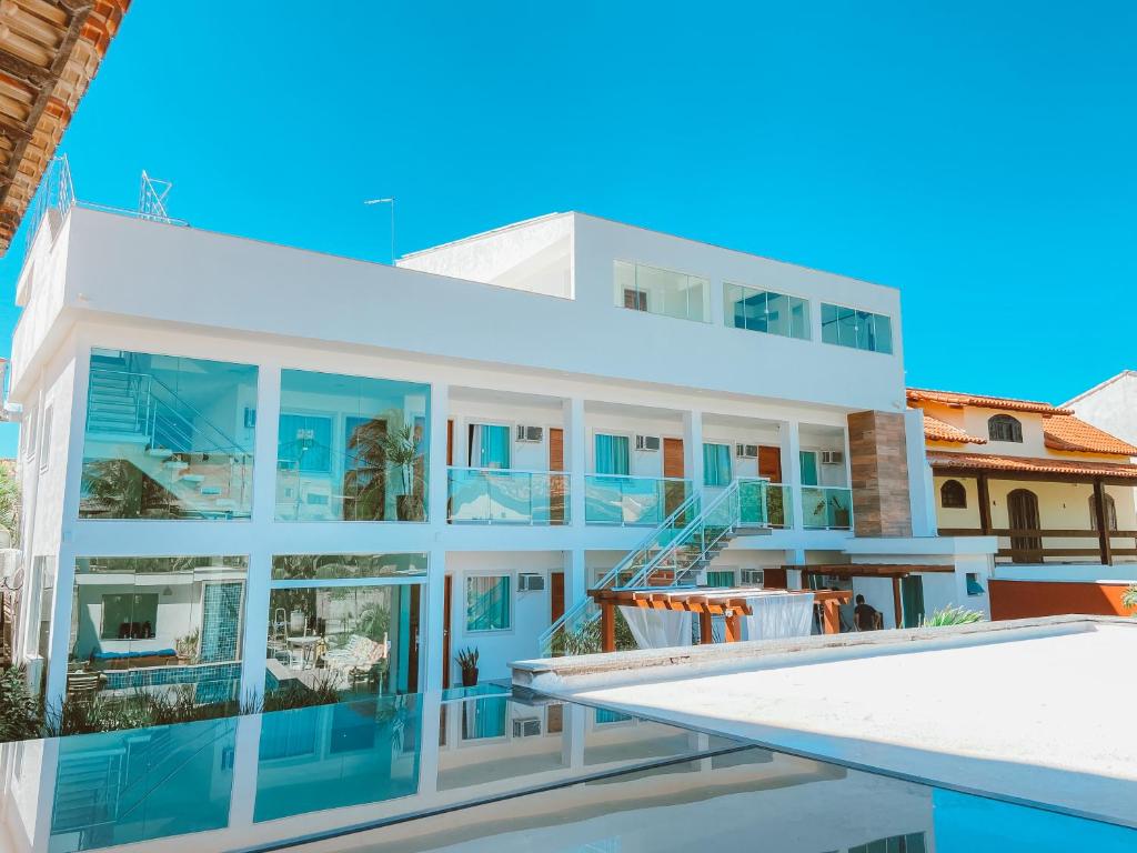 uma casa branca com janelas azuis e uma piscina em Pousada Caminho do Mar em Cabo Frio