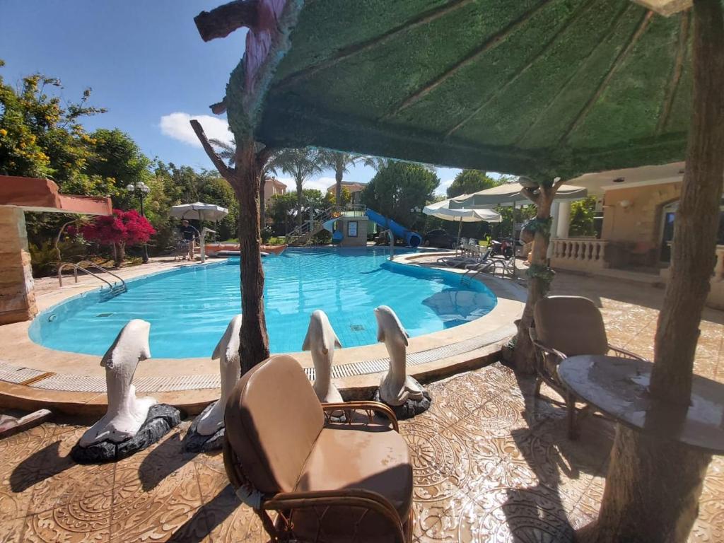 a swimming pool with chairs and an umbrella at Resort altayar Villa altayar 2- Aqua Park in Sidi Kirayr
