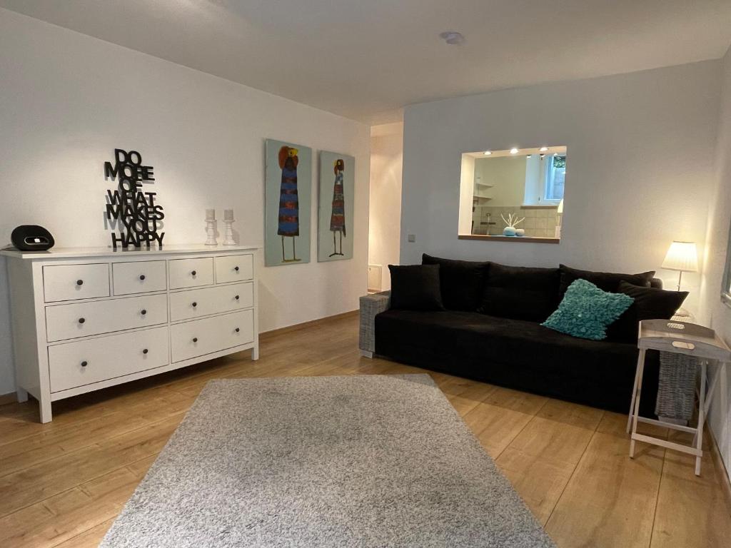 a living room with a black couch and a white dresser at Fewo am kleinen Hafen in Überlingen