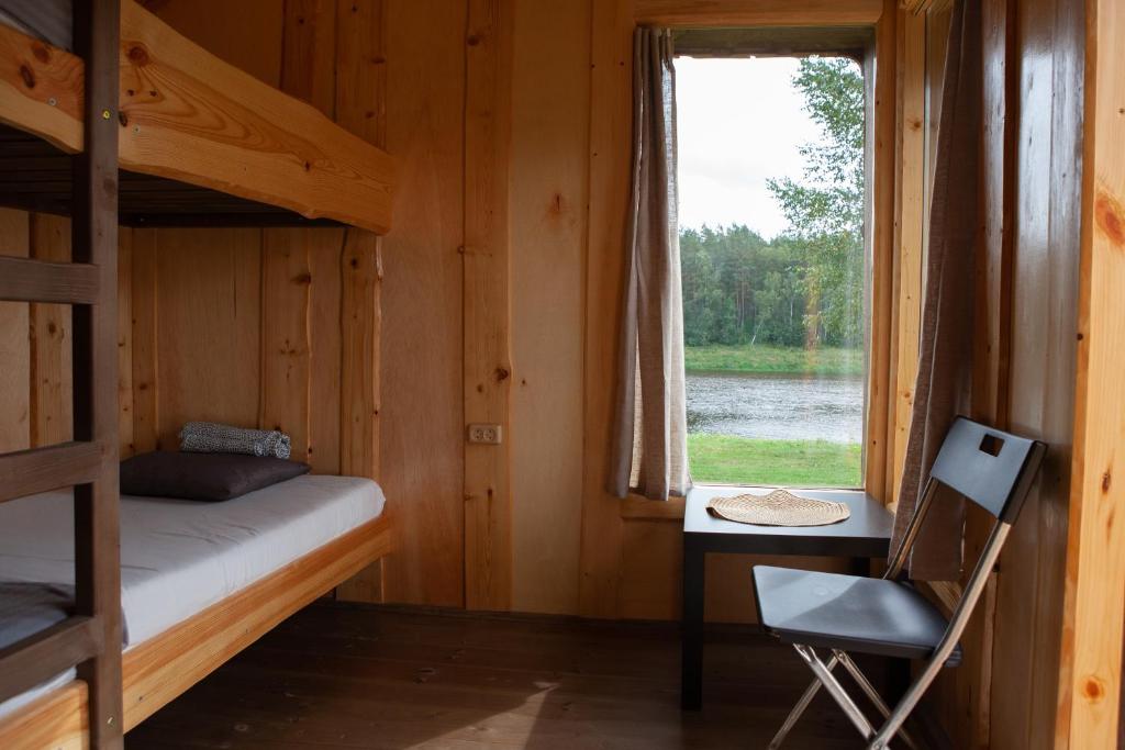 a bedroom with a bunk bed and a desk and a window at Kempings Daugavas lokos in Sargailiški