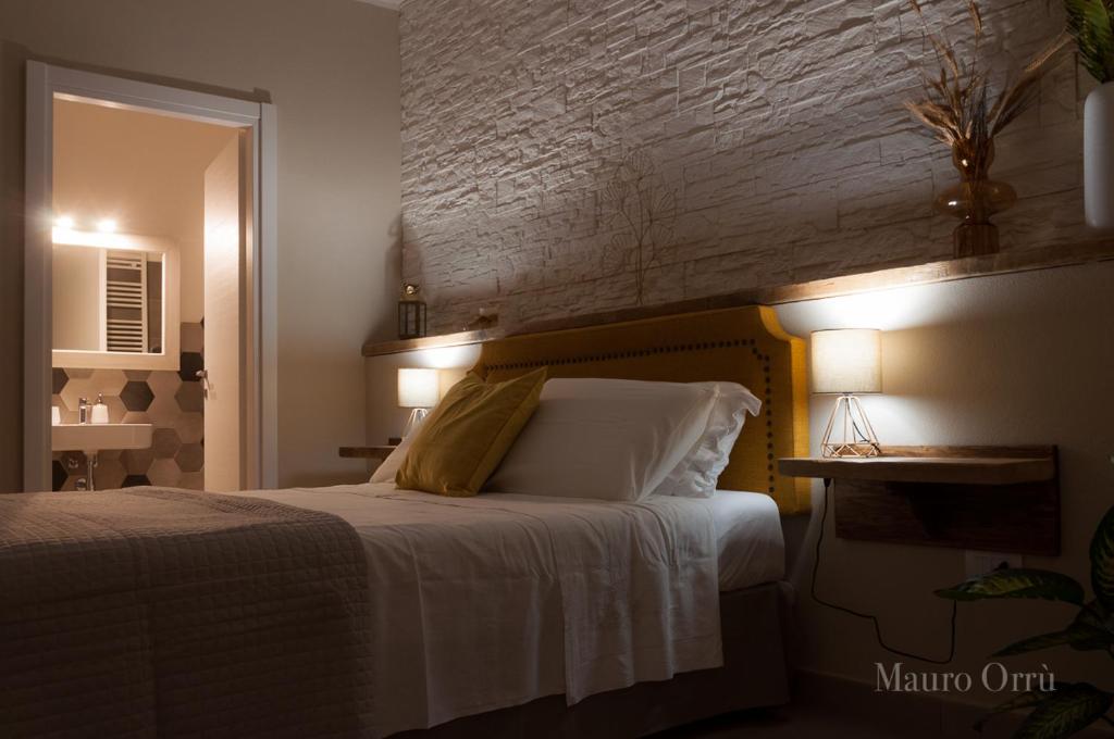 a bedroom with a bed with white sheets and a mirror at NEW HOME - appartamento in centro storico in Cagliari