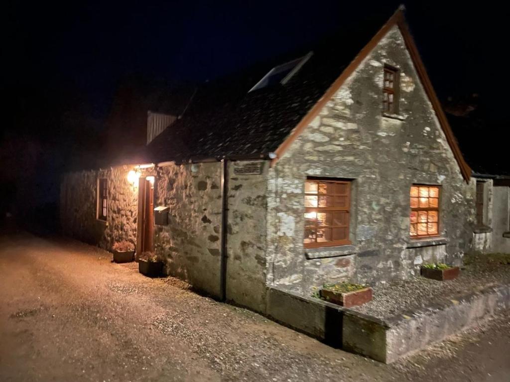 une maison en pierre avec des lumières allumées la nuit dans l'établissement Mawenyoupe, à Lochgilphead