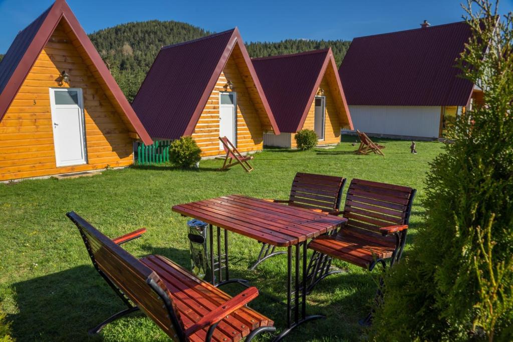 a picnic table and chairs in front of a group of cottages at Cottage Borje in Žabljak