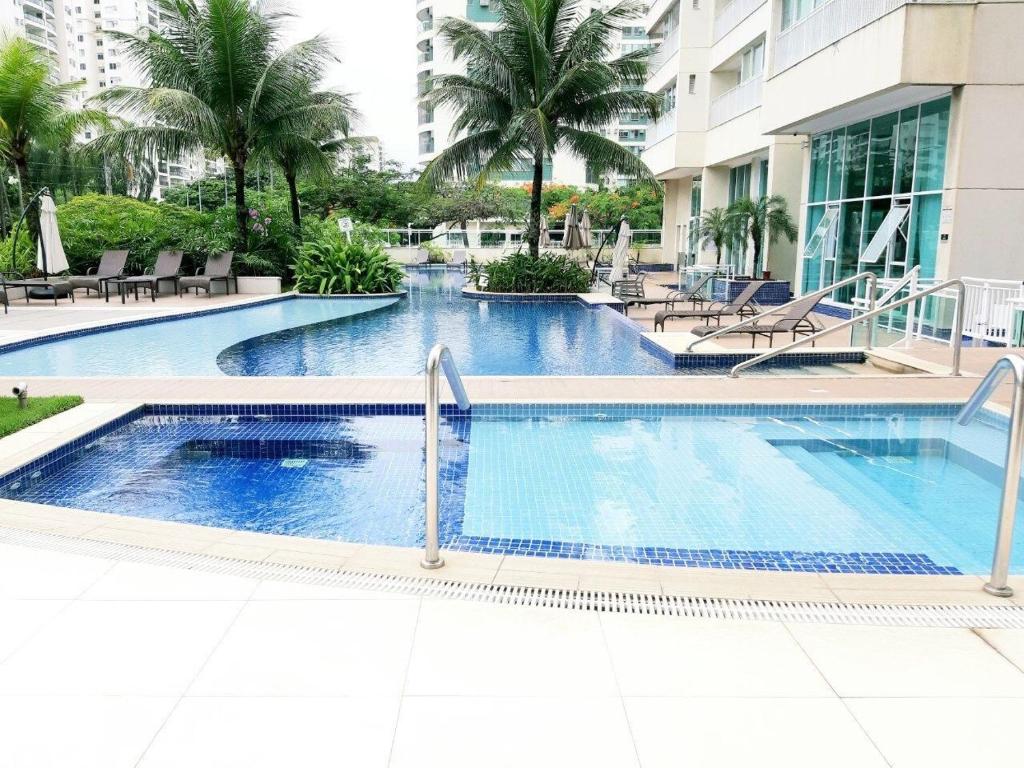 ein Swimmingpool in einem Resort mit Palmen in der Unterkunft Apê na Barra, ao lado do Parque Olímpico, Jeunesse Arena, ar, wi fi, tv a cabo, microondas in Rio de Janeiro