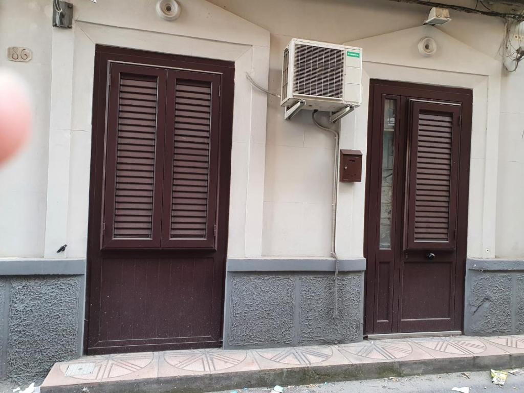 zwei braune Türen in einem Gebäude mit Klimaanlage in der Unterkunft La Casetta in Palermo